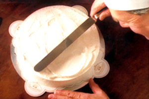 Sahnecreme wird auf einer halbfertigen Torte verstrichen